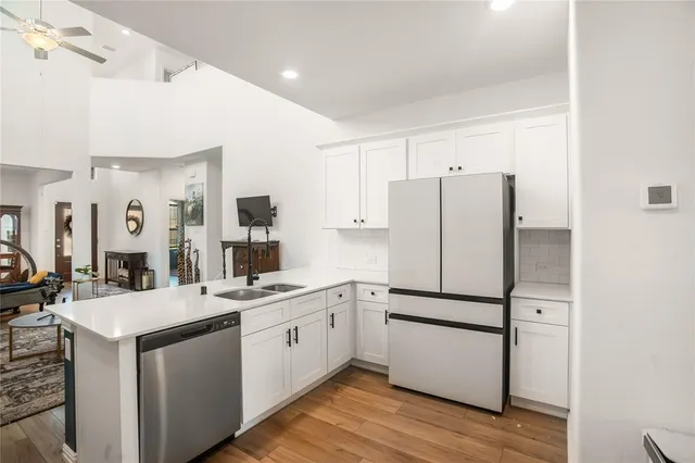 a kitchen with a sink cabinets stainless steel appliances and wooden floor
