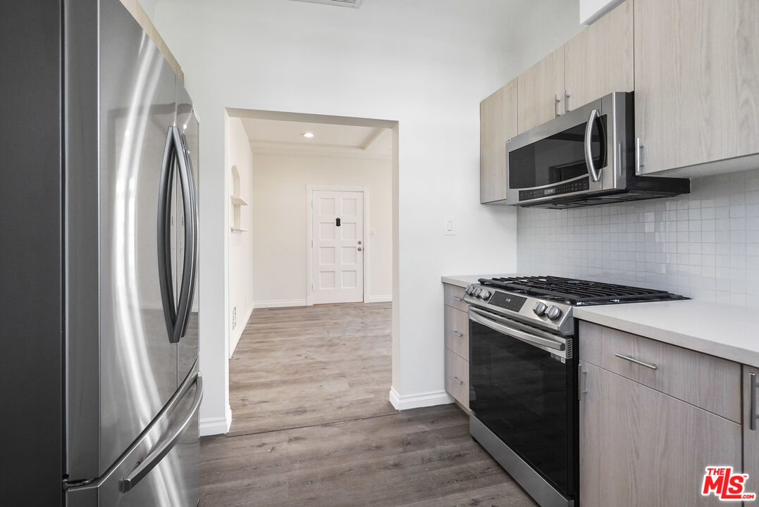 228 South Reeves Drive, Unit D Beverly Hills, CA 90212 - Photo 7 of 13 a kitchen with stainless steel appliances a white stove a microwave and a refrigerator