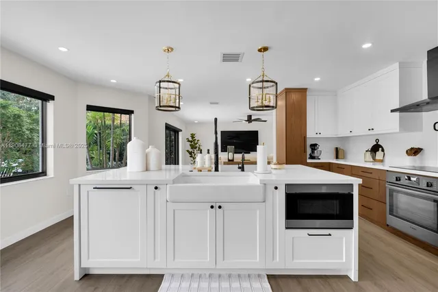 a kitchen with stainless steel appliances a sink cabinets and wooden floor