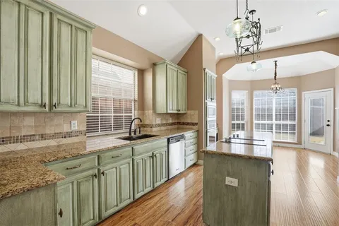 a kitchen with stainless steel appliances granite countertop a sink a stove cabinets and wooden floor