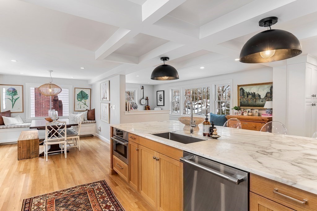 91 Valley Road Milton, MA 02186 - Photo 11 of 29 a kitchen with stainless steel appliances granite countertop a stove a sink a dining table and chairs with wooden floor