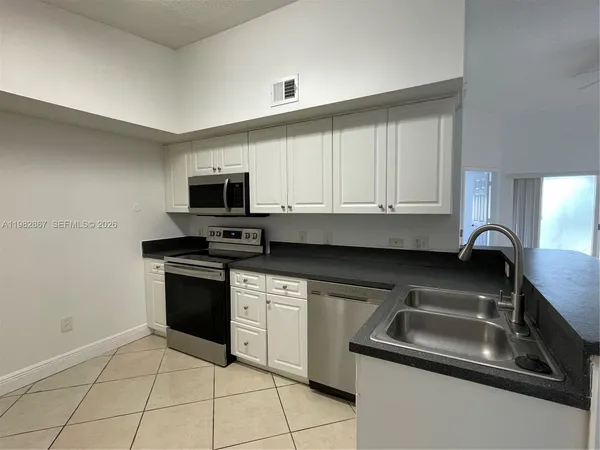 a kitchen with granite countertop a sink stainless steel appliances and white cabinets
