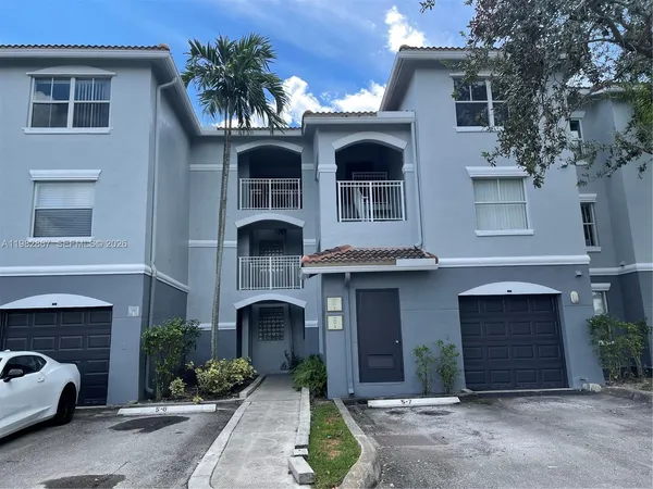 a front view of a house with yard and parking