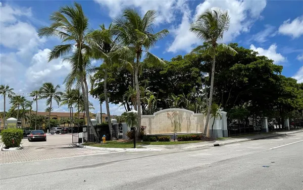 a palm tree sitting in front of a building with trees