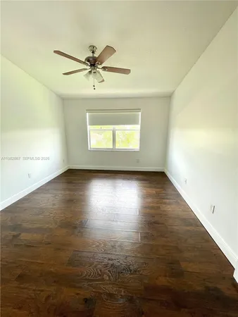 a view of empty room with wooden floor and fan