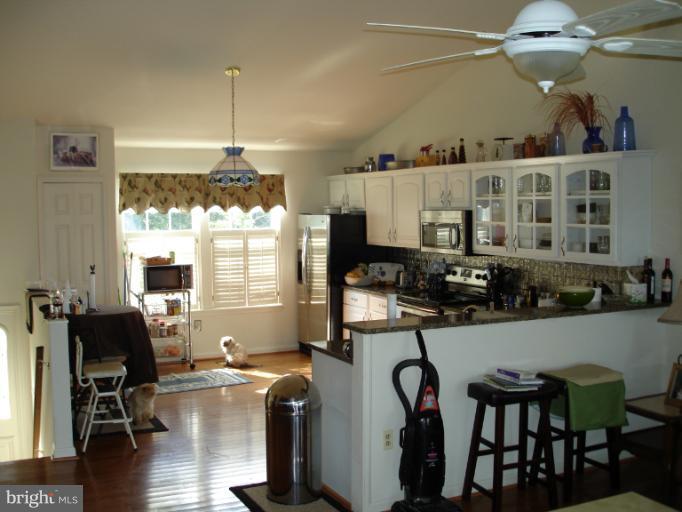 1117 Engleberth Road Essex, MD 21221 - Photo 2 of 20 a kitchen with stainless steel appliances granite countertop a stove top oven a refrigerator a dining table and chairs with wooden floor