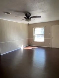 an empty room with wooden floor and windows with curtains
