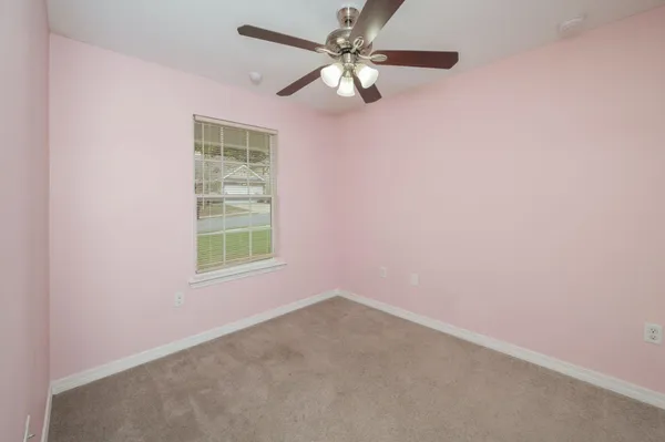 an empty room with a window and a fan