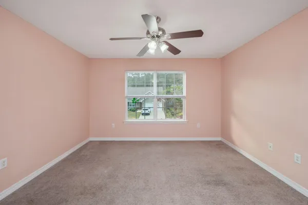 an empty room with a window and a ceiling fan
