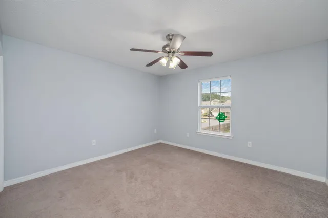 an empty room with a chandelier fan and closet