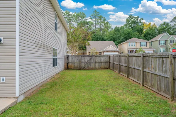 a view of a yard in front of a house with wooden fence