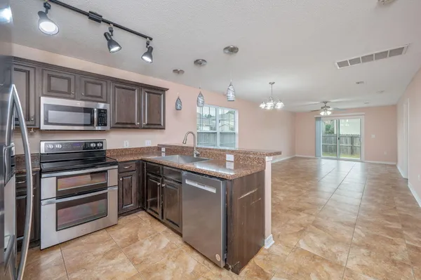 a kitchen with stainless steel appliances granite countertop a stove top oven a sink and a refrigerator