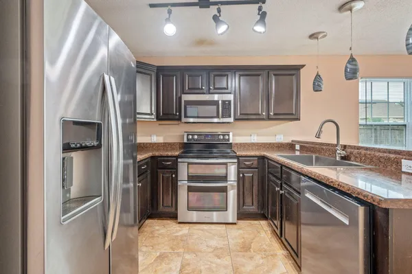 a kitchen with kitchen island granite countertop a stove sink and refrigerator