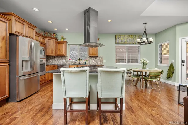 a kitchen with stainless steel appliances a dining table chairs stove refrigerator and cabinets
