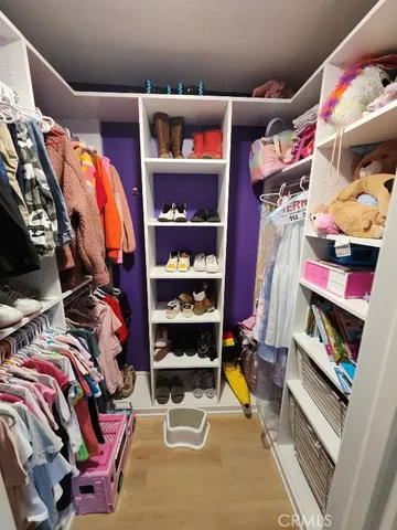 a view of walk in closet with clothes and shoes