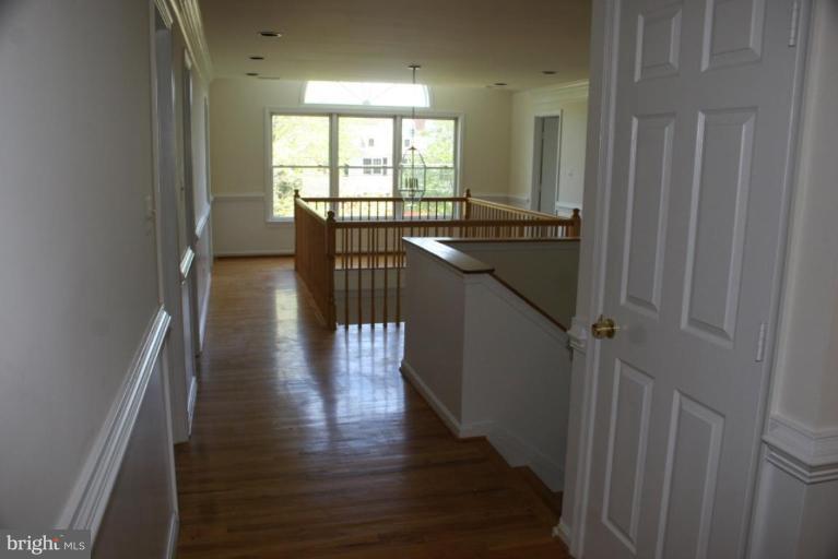 7030 Utica Street Springfield, VA 22150 - Photo 14 of 19 a hallway with wooden floor windows and stairs