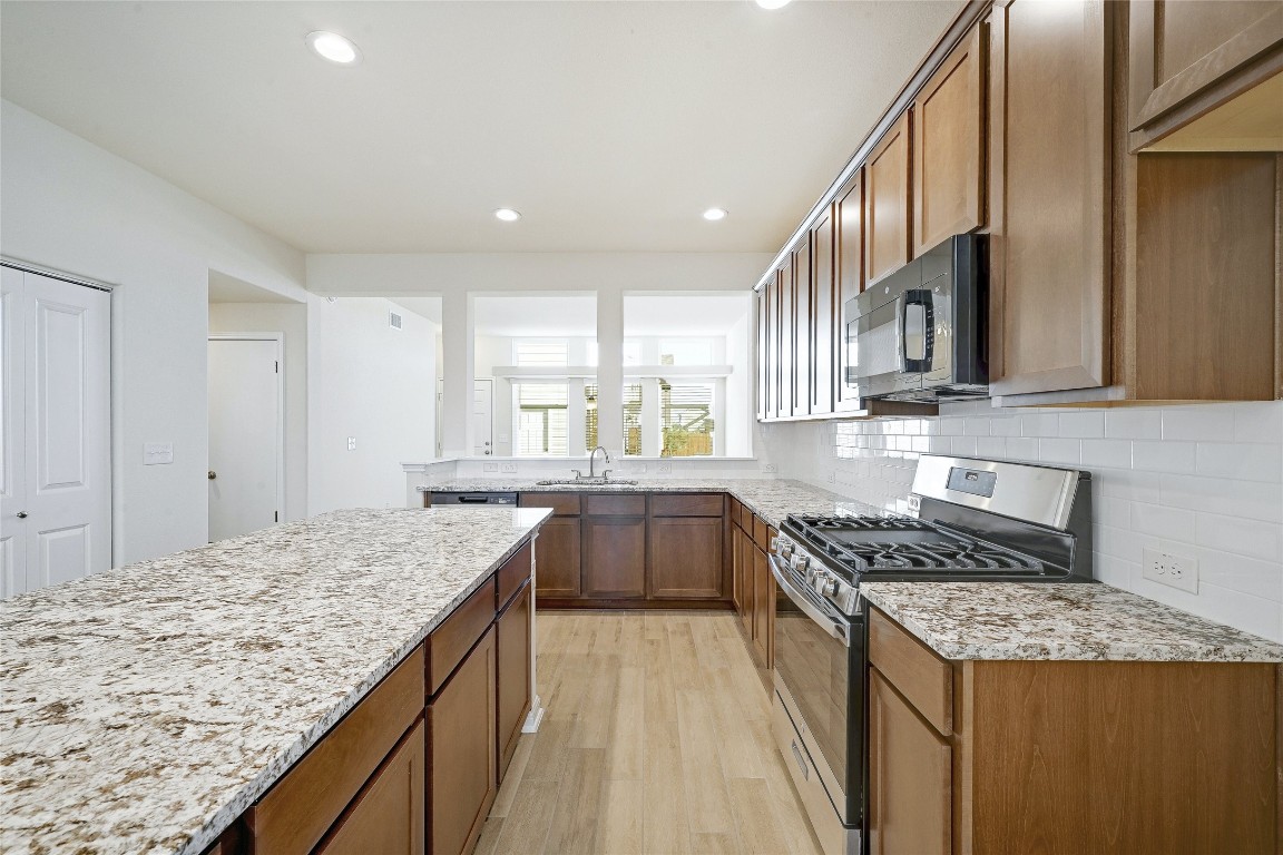 a kitchen with granite countertop sink stove and refrigerator