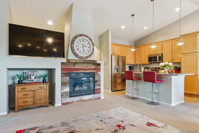 a living room with furniture a fireplace and a kitchen view