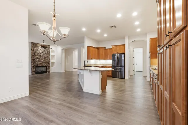 a kitchen with stainless steel appliances granite countertop a refrigerator a sink dishwasher a stove and white countertops with wooden floor