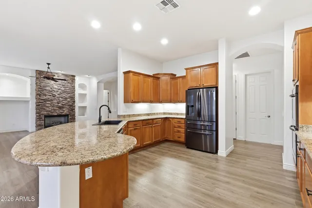 a view of an empty room with a kitchen and wooden floor