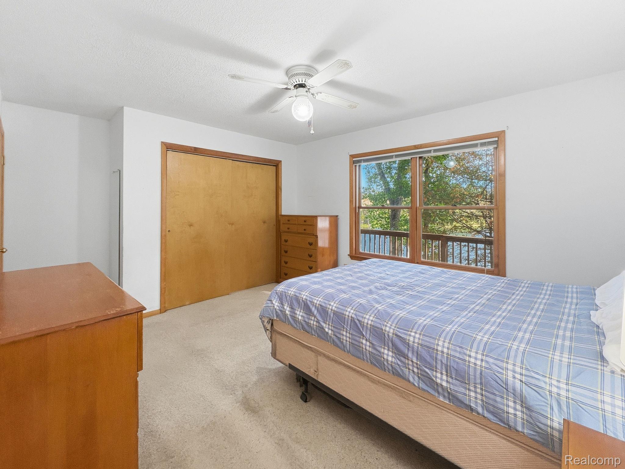 2259 Kassuba Road Gaylord, MI 49735 - Photo 18 of 46 Window with exterior scenery, wood-frame window, ceiling fan, carpeting, and wood-finish closet doors