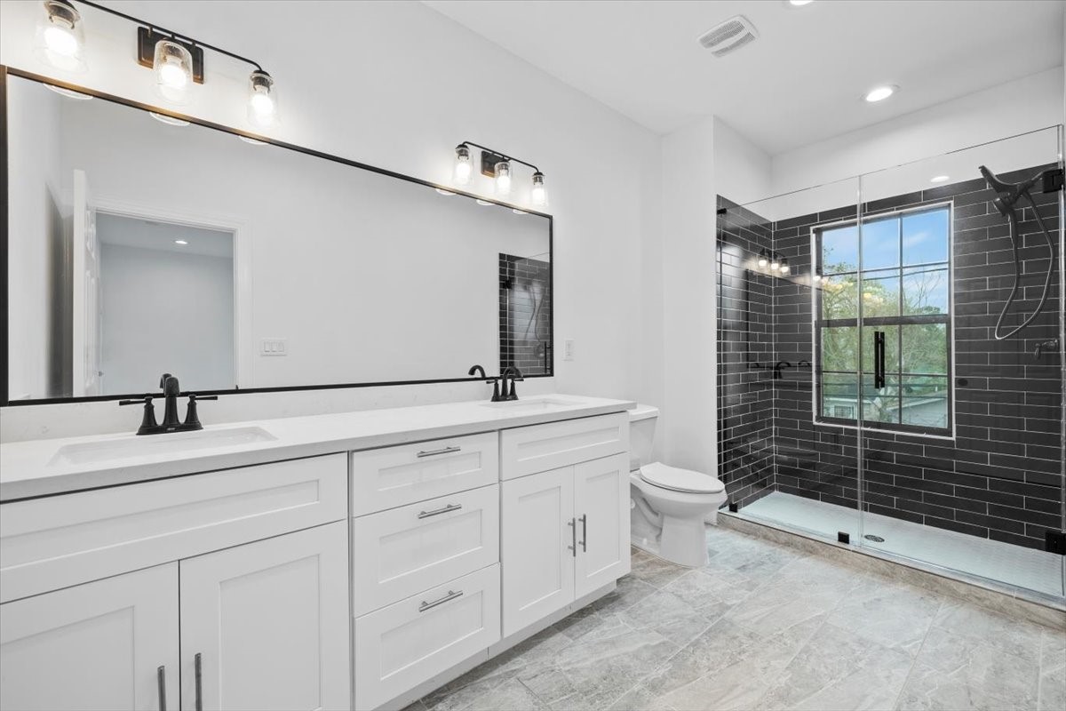 727 East 40th Street Houston, TX 77022 - Photo 14 of 22 a spacious bathroom with double sink a toilet a mirror and shower