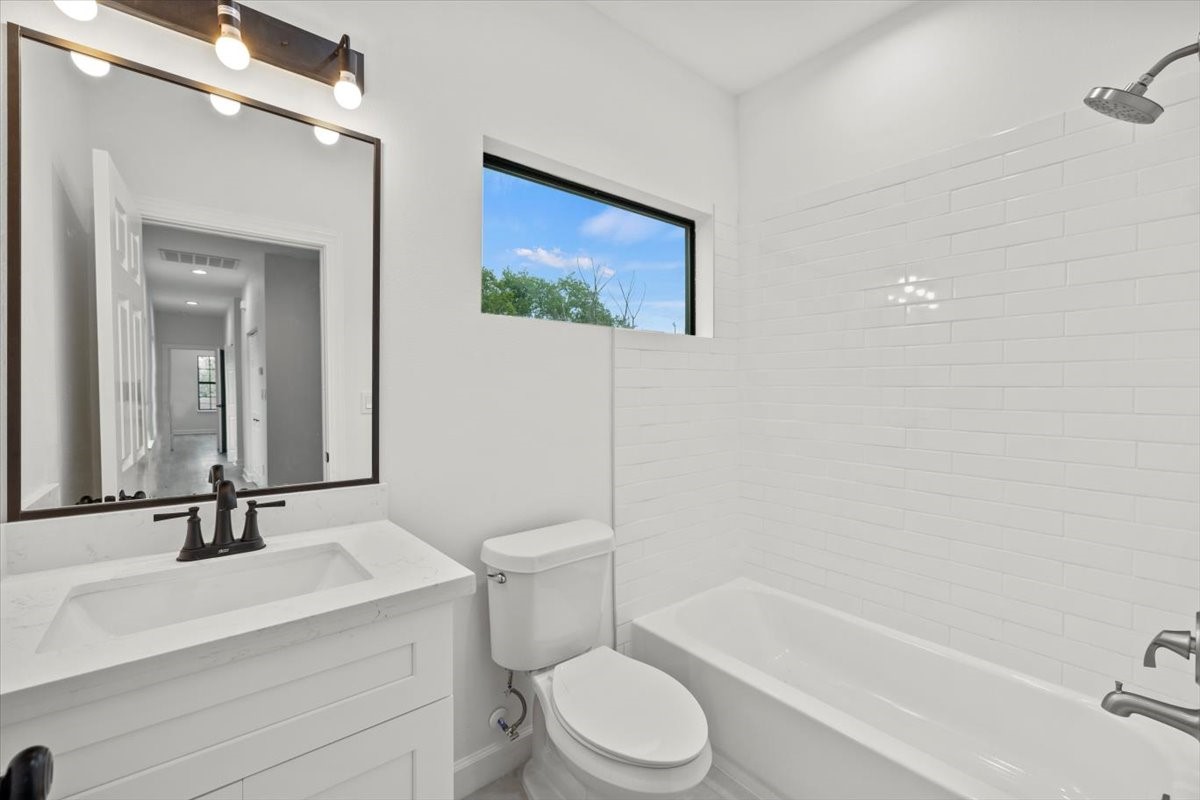 727 East 40th Street Houston, TX 77022 - Photo 19 of 22 a bathroom with a toilet a sink a mirror and a bathtub