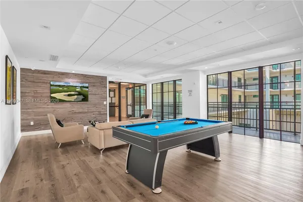 a room with furniture pool table wooden floor and windows