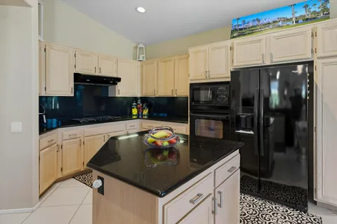 a kitchen with granite countertop a refrigerator a stove a microwave and cabinets