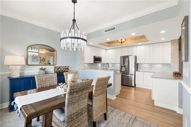 a view of a dining room and livingroom with furniture wooden floor a rug a chandelier
