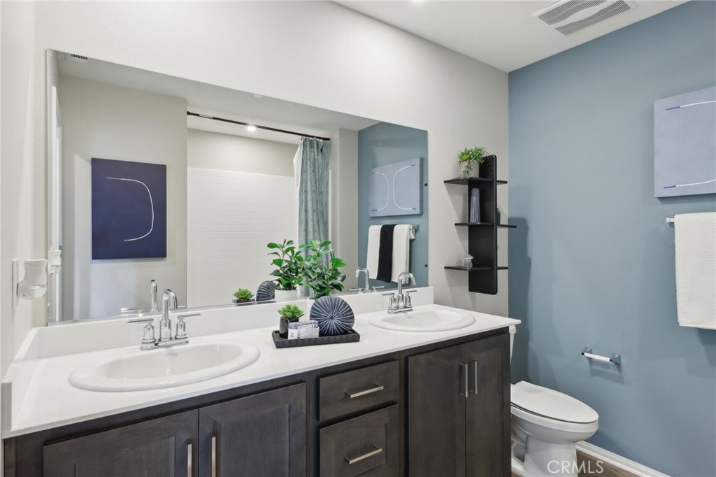 15535 April Dawn Way, Unit 1 Fontana, CA 92336 - Photo 11 of 16 a bathroom with a double vanity sink toilet and mirror