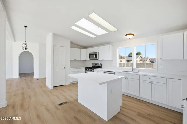 a kitchen with kitchen island granite countertop a sink cabinets and wooden floor