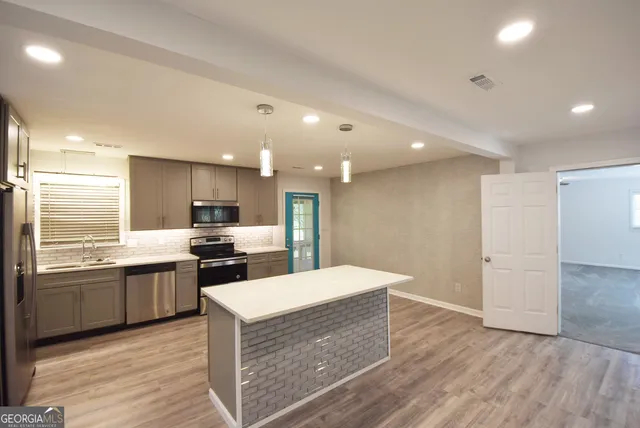 a kitchen with kitchen island a sink stainless steel appliances and cabinets