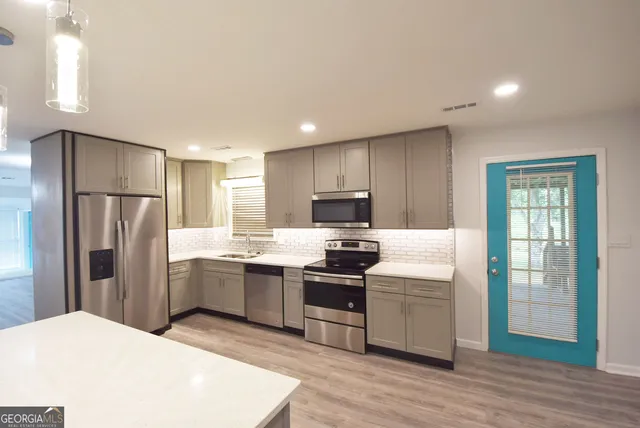 a large kitchen with a refrigerator a sink dishwasher and a stove with wooden floor