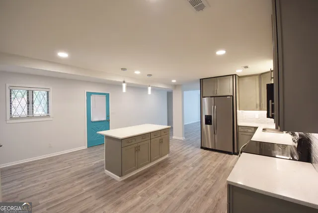 a large white kitchen with a stove a sink dishwasher and a refrigerator with wooden floor