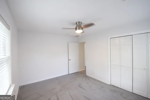 an empty room with a window and a ceiling fan