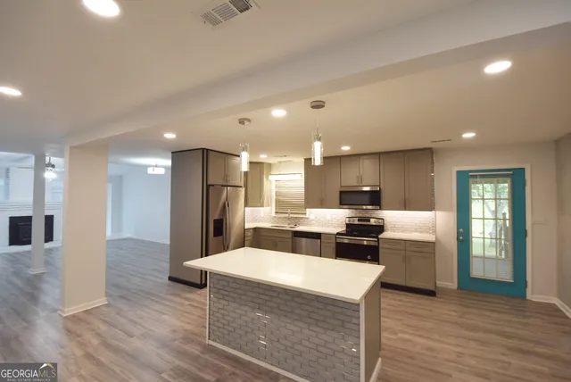 a large kitchen with kitchen island a stove a sink a refrigerator and white cabinets with wooden floor