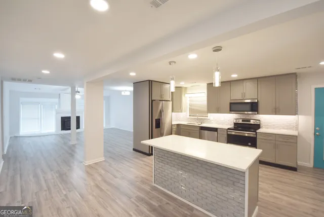 a large kitchen with stainless steel appliances kitchen island a large counter top and a refrigerator