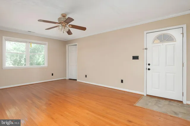 a view of an empty room with wooden floor and window