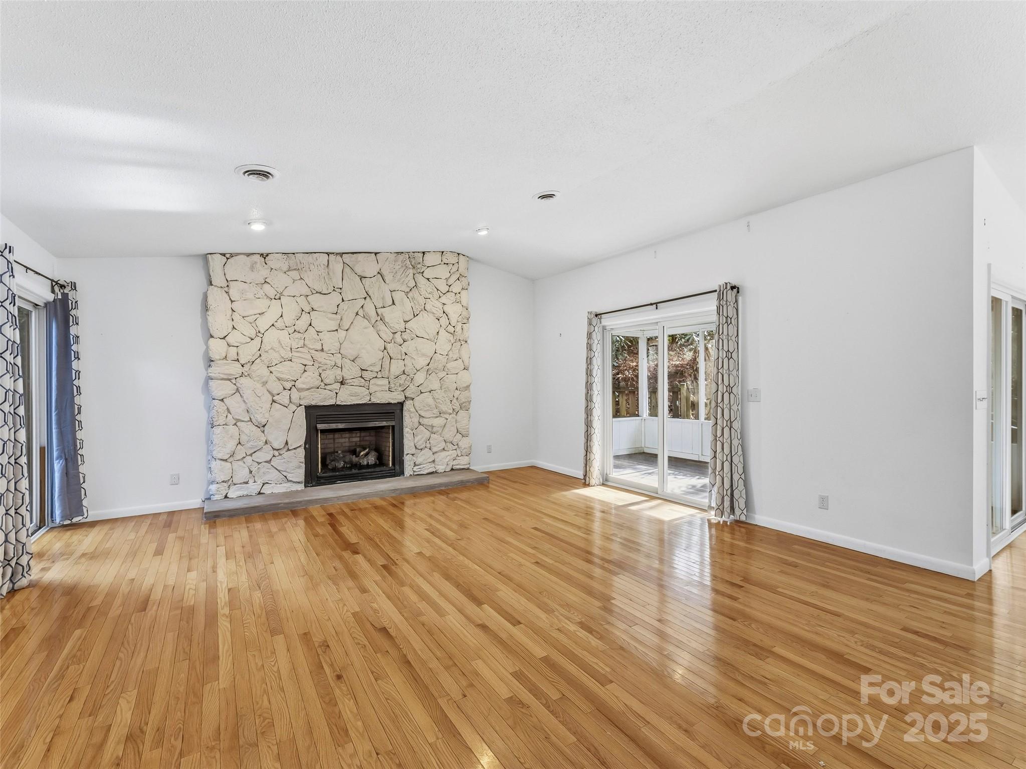 27 Spring Valley Road Pisgah Forest, NC 28768 - Photo 12 of 37 a view of an empty room with wooden floor fireplace and a window