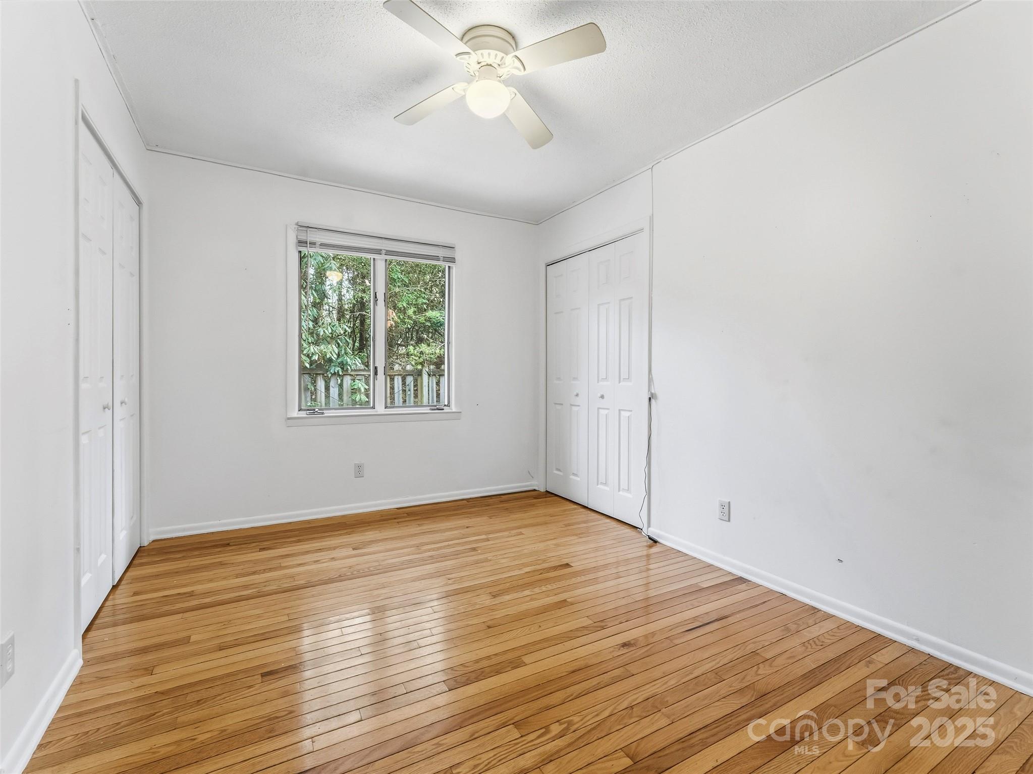 27 Spring Valley Road Pisgah Forest, NC 28768 - Photo 18 of 37 an empty room with wooden floor chandelier fan and windows