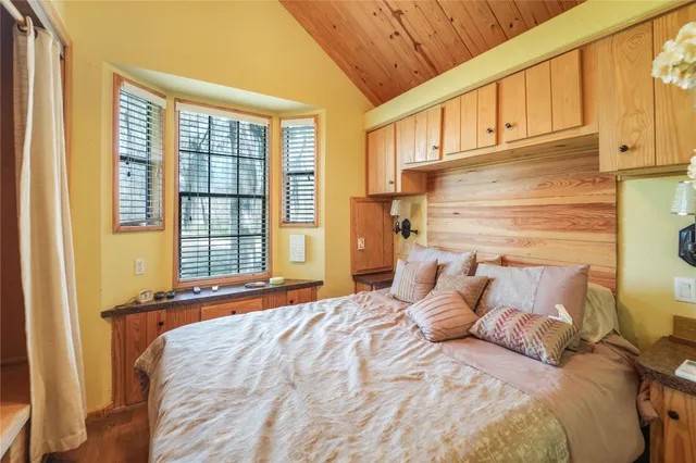 a bedroom with a bed a dresser and next to a window