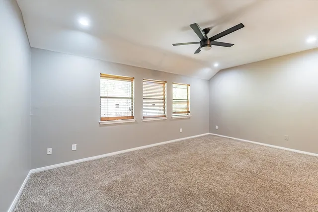 an empty room with ceiling fan and windows