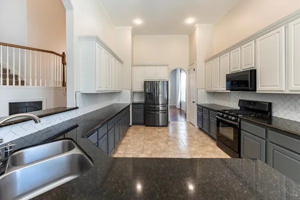 a kitchen with stainless steel appliances granite countertop a sink a stove top oven a refrigerator and white cabinets