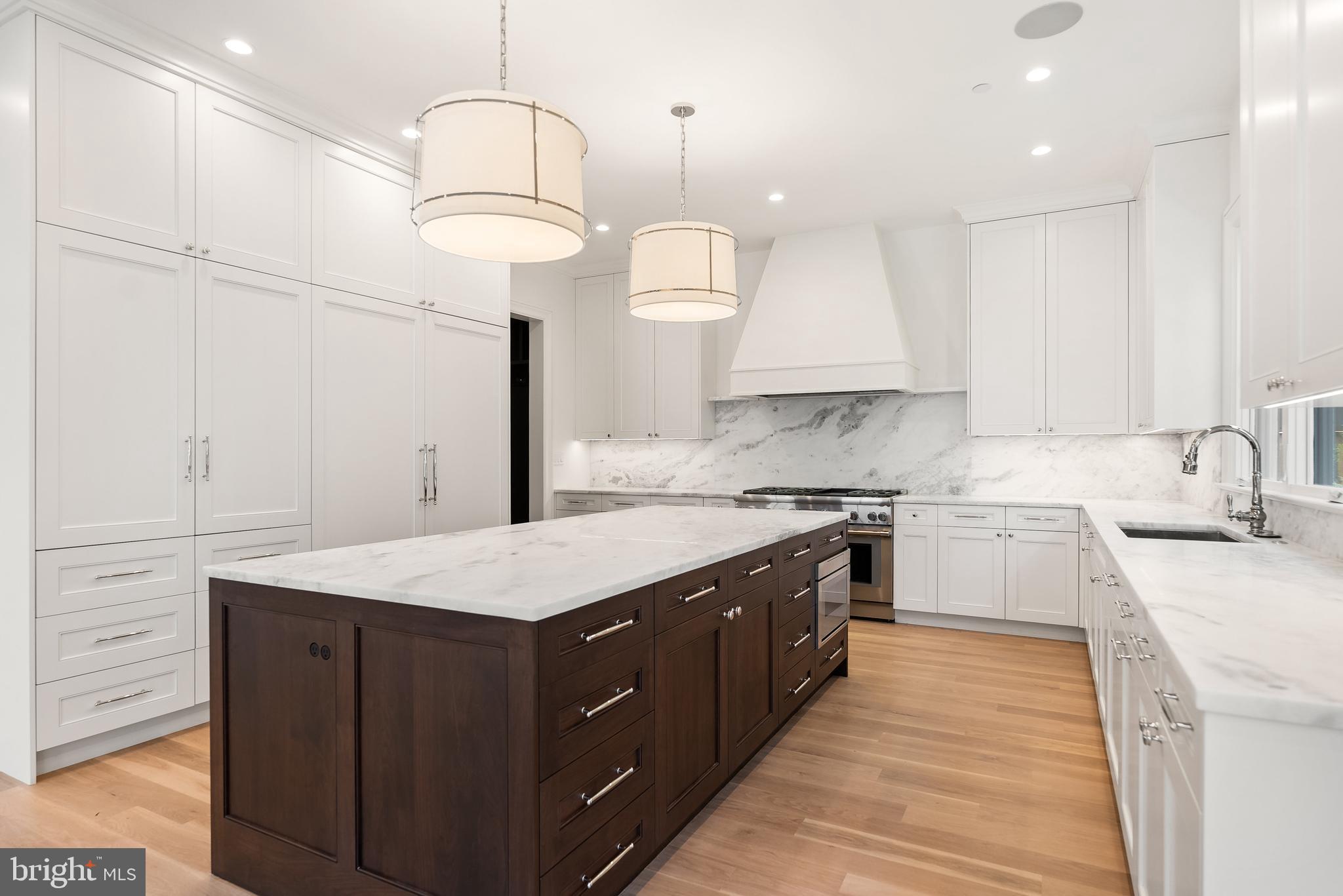 4905 Van Ness Street Northwest Washington, DC 20016 - Photo 5 of 27 a kitchen with a sink dishwasher a stove and a dining table with wooden floor