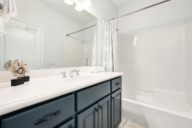 a bathroom with a sink vanity granite tub shower and a mirror