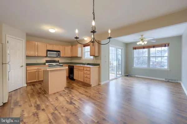 a kitchen with a stove a sink dishwasher a refrigerator and white cabinets with wooden floor