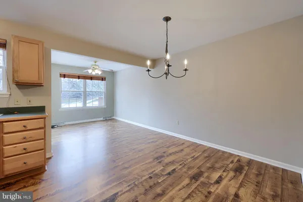 a view of empty room with wooden floor fan and window