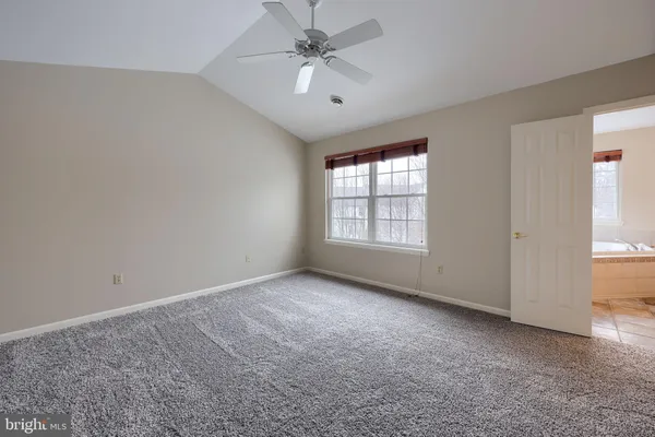 an empty room with windows and ceiling fan