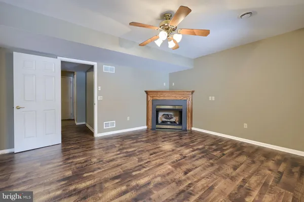 an empty room with wooden floor chandelier fan and windows